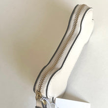 Load image into Gallery viewer, Close-up of a white shoe with a gold zipper on a beige background