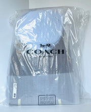 Load image into Gallery viewer, A Coach New York garment wrapped in clear plastic packaging with the Coach logo printed on the front, photographed against a plain light background.