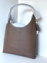 Load image into Gallery viewer, A Coach hobo shoulder bag in taupe brown leather, shown with protective white plastic wrapping on the handle and a hanging brand tag, set against a plain white background.