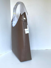 Load image into Gallery viewer, A brown leather tote bag with a structured rectangular silhouette, featuring a top handle, a hanging leather tag, and a white product tag, photographed against a plain white background.