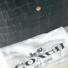 Load image into Gallery viewer, Dark textured bag with a gold button on top of a white Coach New York dust bag.