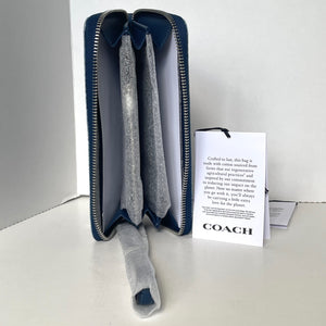 Blue zippered pouch with gray interior and Coach branded card on a white background