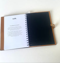 Load image into Gallery viewer, An open spiral-bound leather journal or notebook on a white surface, showing a brown leather cover, a printed white page with text, and a black interior cover.