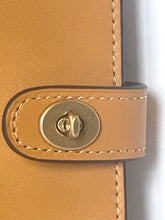 Load image into Gallery viewer, Close-up of a tan leather strap with matching stitching and a round brass snap closure on a light gray background.