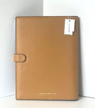 Load image into Gallery viewer, A tan leather planner cover with a side tab closure and a white hangtag, photographed against a white background.