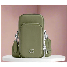 Load image into Gallery viewer, Green crossbody bag with keychains on a white platform against a pink background