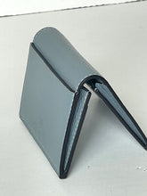 Load image into Gallery viewer, A light gray textured leather wallet standing open on a light gray surface.