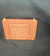 Load image into Gallery viewer, A brown leather patch with embossed text and gold-colored stitching details, placed on a dark textured fabric background.