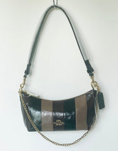 Load image into Gallery viewer, A Coach shoulder bag with a black and brown striped leather body, a gold-tone chain strap, and a black leather hangtag, shown hanging against a plain white wall.