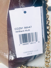 Load image into Gallery viewer, Close-up of a handbag tag attached to a brown textured bag with a gold chain strap. The white tag shows the text 'CDZ91 IMA47 IM/Black Multi' and a barcode.