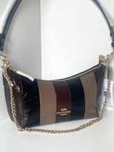 Load image into Gallery viewer, A Coach crescent-shaped shoulder bag with vertical glossy stripes in black, brown, and taupe, featuring a gold-tone chain strap and a gold Coach logo on the front.