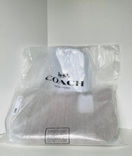 Load image into Gallery viewer, A Coach New York garment or accessory wrapped in a clear plastic bag, with the Coach logo printed on the front, photographed against a plain light background.
