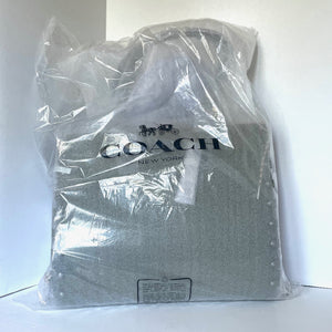 Coach tote bag wrapped in clear plastic on a white background