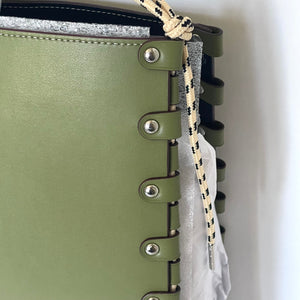 Close-up of a green leather-bound notebook with metal rings and a rope detail.