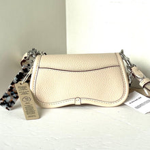 Load image into Gallery viewer, Beige handbag with chain strap on a white surface, accompanied by tags.