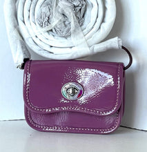 Load image into Gallery viewer, A small glossy purple handbag with a silver-tone turn-lock closure, shown with a white scarf wrapped in plastic behind it against a plain white wall.