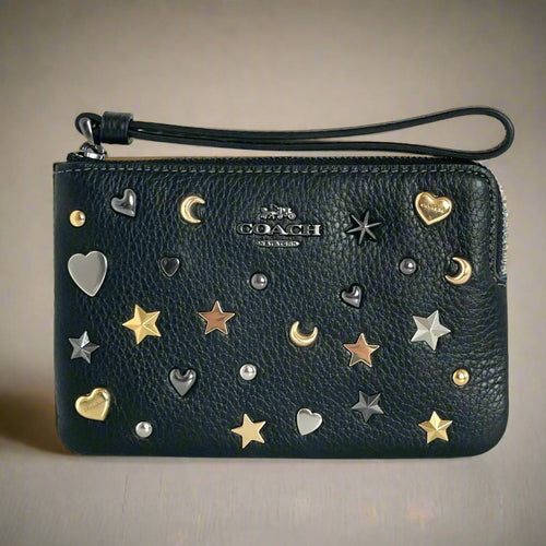 Black Coach wallet with star, moon, and heart embellishments on a white background