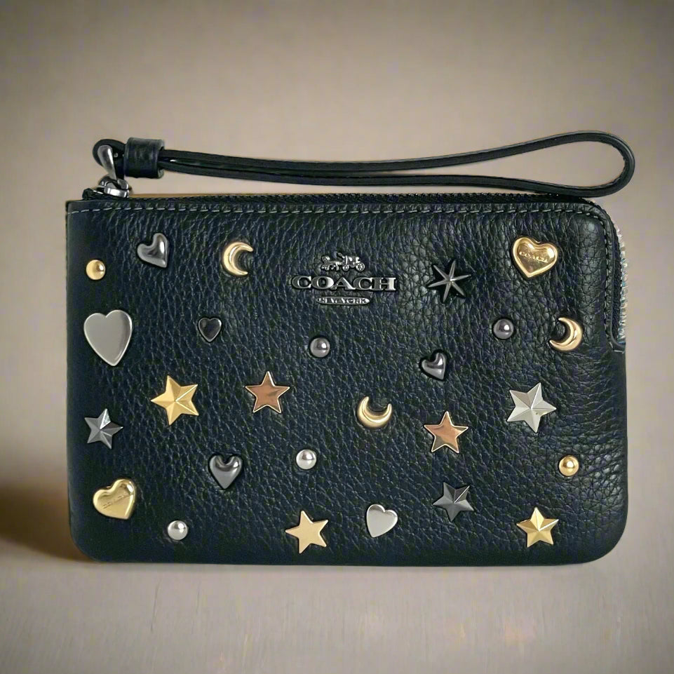 Black Coach wallet with star, moon, and heart embellishments on a white background