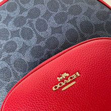 Load image into Gallery viewer, Close-up of a red Coach bag with a gold logo on a gray textured background