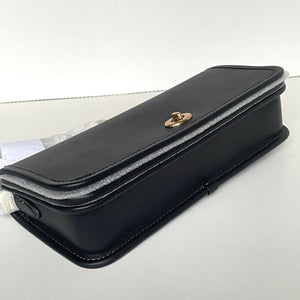 Black leather clutch bag with gold clasp on a light gray background