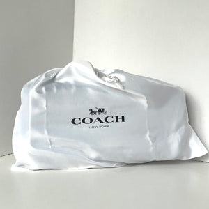 Coach bag wrapped in a satin cover on a light gray background