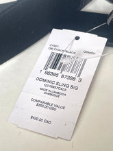 Load image into Gallery viewer, A white paper retail hangtag attached to a garment with a barcode and printed text including 'DOMINIC SLING SIG' and 'Made in Cambodia'.