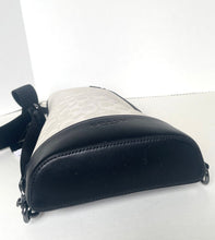 Load image into Gallery viewer, A Coach crossbody bag in black and beige monogram canvas, shown from a side angle on a white surface.