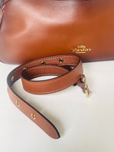 Load image into Gallery viewer, Brown leather Coach handbag with strap on a white background