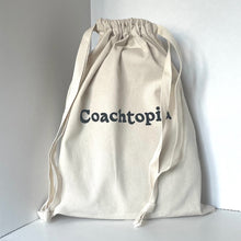 Load image into Gallery viewer, Beige drawstring bag with &#39;Coachtopia&#39; branding on a white background