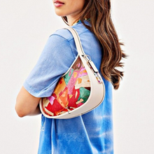 Load image into Gallery viewer, Woman wearing a colorful coach ergo leather handbag with a white background