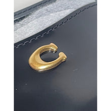 Load image into Gallery viewer, Gold hook on a black leather surface