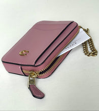 Load image into Gallery viewer, A pink Coach crossbody phone bag with gold hardware, a gold C logo on the front, and a gold chain strap, resting on a light off-white surface.