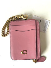 Load image into Gallery viewer, A pink leather Coach card holder and phone pouch with a gold-tone chain strap, a gold 'C' logo, and a white branded tag on a white background.