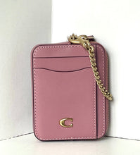 Load image into Gallery viewer, A pink leather card holder wallet with a gold-tone chain strap and a gold 'C' logo, standing on a white surface against a white background.