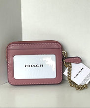 Load image into Gallery viewer, A Coach card holder wristlet in dusty rose pink leather with a clear ID window, gold-tone chain strap, and attached white COACH hangtag, photographed against a light neutral background.