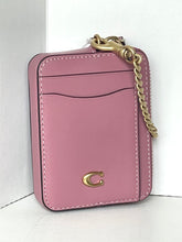 Load image into Gallery viewer, A pink leather crossbody phone bag with a gold-tone chain strap and a gold 'C' logo on the front, photographed in a white corner.