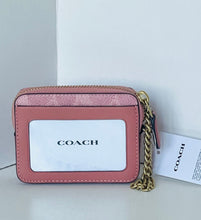 Load image into Gallery viewer, A Coach crossbody card holder in dusty pink textured leather with a gold-tone chain strap and a white ID window displaying the Coach logo. A white branded hangtag is attached next to the bag.