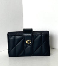 Load image into Gallery viewer, A black quilted leather wallet with a gold-tone 'C' logo clasp, standing on a light gray surface against a white background.