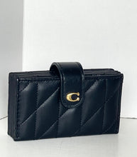 Load image into Gallery viewer, A black quilted leather clutch wallet with a gold-tone 'C' logo clasp, displayed on a light gray surface against a white background.