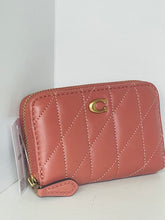 Load image into Gallery viewer, A Coach quilted zip-around wallet in dusty rose pink leather with gold-tone hardware and a signature 'C' logo, shown with its retail tag attached against a plain white background.