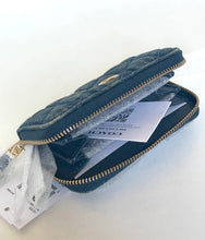 Load image into Gallery viewer, A Coach quilted dark gray denim wallet with gold-tone zippers and hardware, shown open with its original tags and warranty card visible inside.