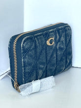 Load image into Gallery viewer, A dark blue quilted leather wallet with gold-tone hardware and a gold 'C' logo, shown with its protective bubble wrap packaging on a white surface.
