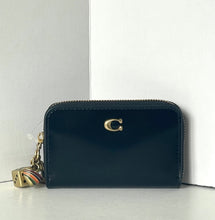 Load image into Gallery viewer, Black wallet with a gold charm on a white background