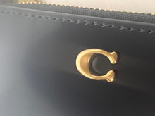 Load image into Gallery viewer, Gold horseshoe charm on a black leather surface