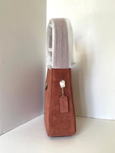 Load image into Gallery viewer, Brown handbag with a gray towel draped over it on a white surface.