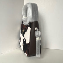 Load image into Gallery viewer, Brown and white cow print handbag with clear plastic wrap on a white background