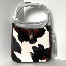 Load image into Gallery viewer, Coach handbag with cow print pattern on a white background