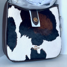 Load image into Gallery viewer, Coach handbag with cow print pattern on a white background