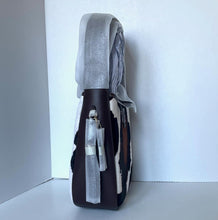 Load image into Gallery viewer, Backpack with a gray hood leaning against a white wall on a white floor