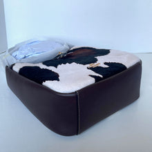 Load image into Gallery viewer, Black and white cowhide leather bag on a light blue background
